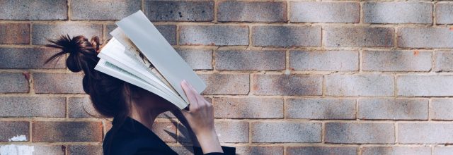 ihminen pitää kirjaa kasvojensa päällä