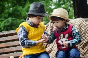 Kaksi lasta jakavat ruokaa puistonpenkillä