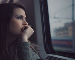 Nuori nainen mietiskelee yksin junassa 