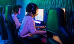 Nuori nainen ja nuori mies pelaavat videopeliä pelitietokoneella ja kuulokkeilla