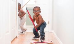 Pieni, silmälasipäinen poika pesee lattiat mopilla