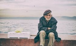 Yksinäinen ikääntynyt mies istuu meren äärellä