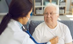 Naislääkäri kuuntelee ikääntyneen miehen sydäntä