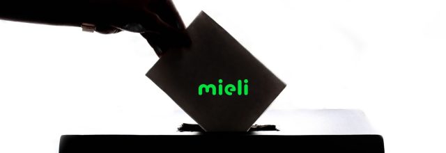 Käsi laittaa äänestyspaperin laatikkoon. MIELI Suomen mielenterveys ry:n vihreällä logolla.