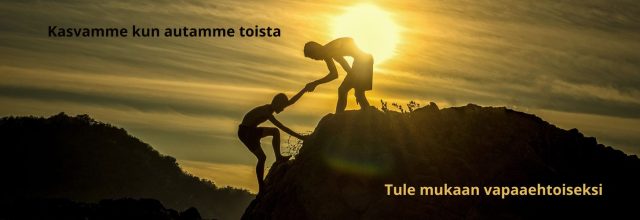 Mies auttaa poikaansa vuorenhuipulle auringonlaskun alla